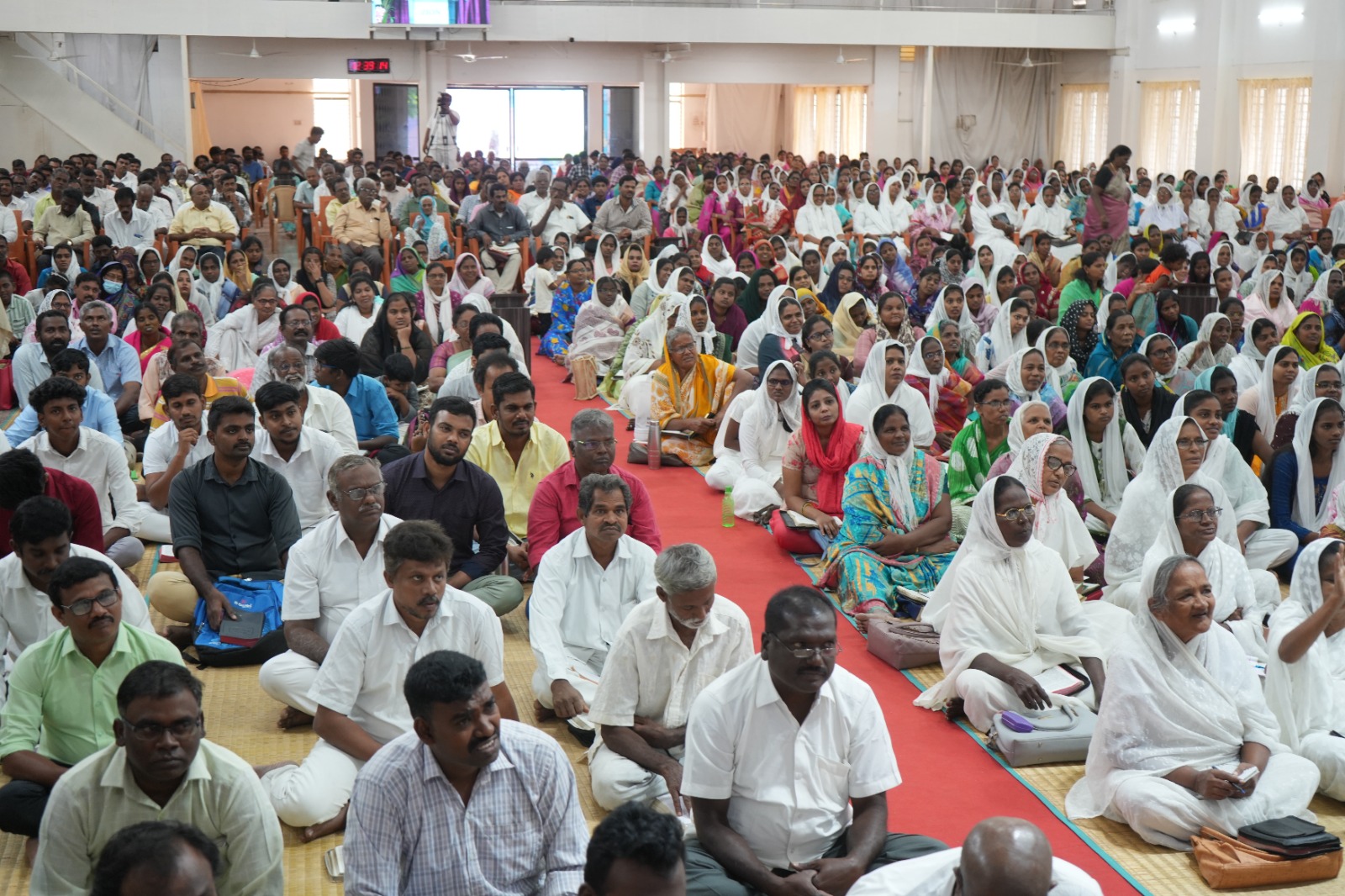 Hundreds of believers seated on the floor at a conference in India