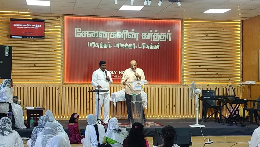Abel Govender ministering from the platform at a church in India